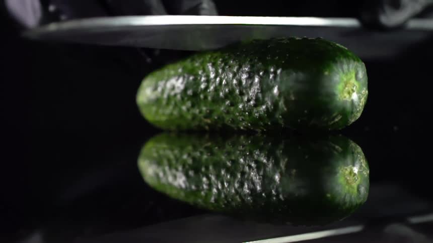 A person cuts the pickle with a knife