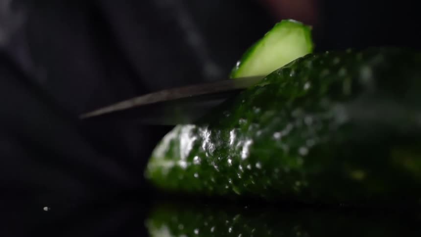 A knife cuts through a green vegetable