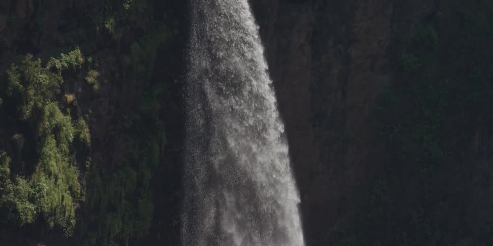 Water is pouring down from a waterfall on a sunny day