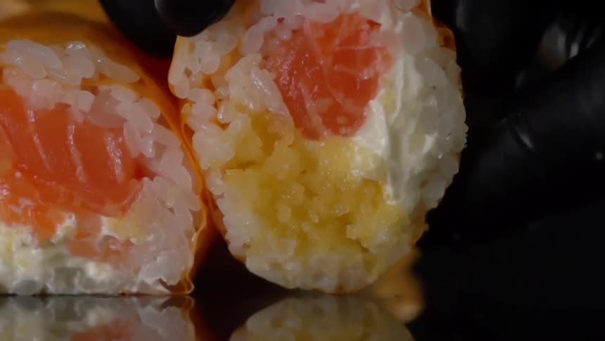 Black gloved hand places round food next to another piece of round food