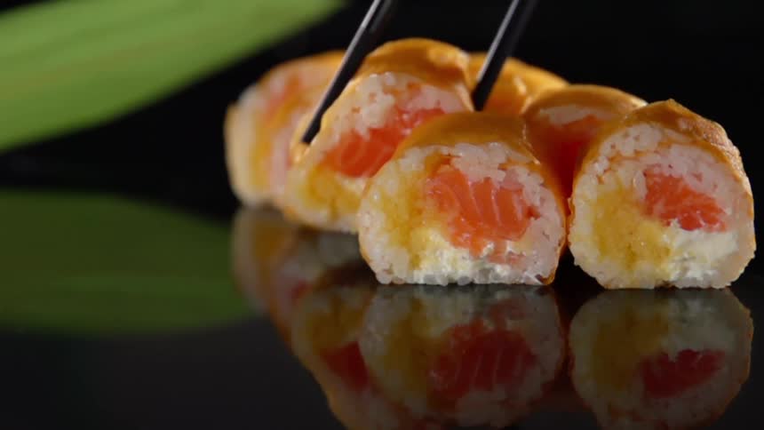 A piece of sushi being picked up with chop sticks