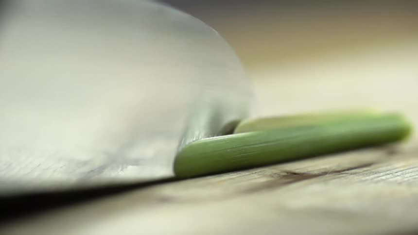 A person cuts a stalk of scallion