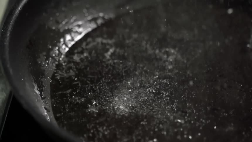 Oil cooking on a wok with the oil bubbling and splashing