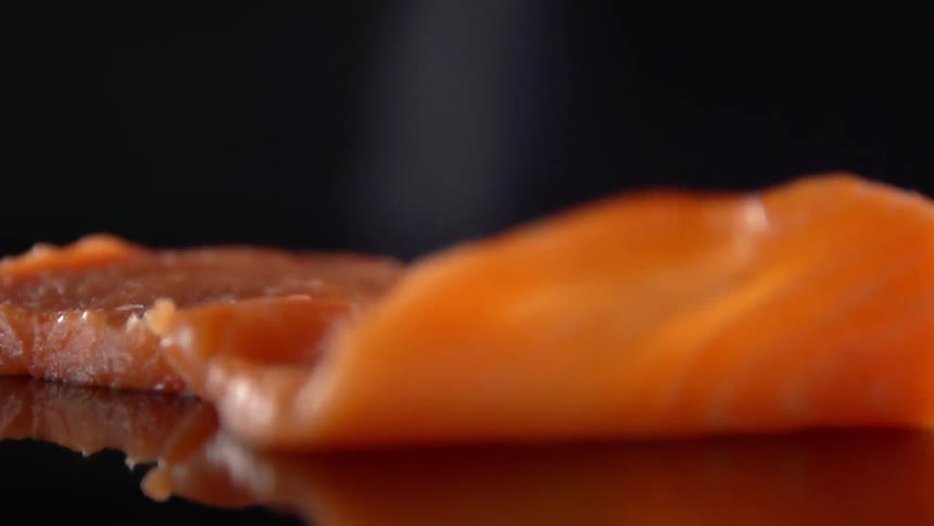 A piece of salmon being laid down on a counter top