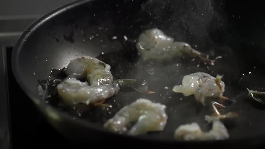 Shrimp falling into a frying pan with oil