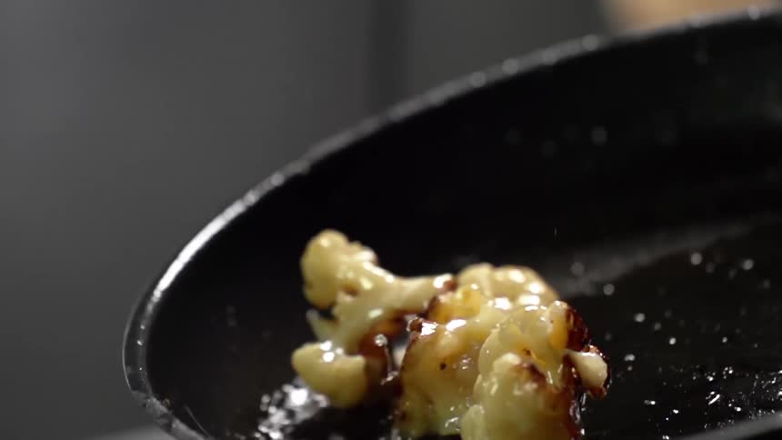 Cauliflower tossing in a frying pan with vegetable oil