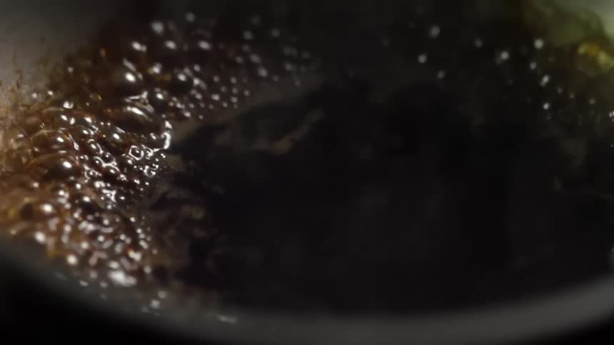 A soy sauce being boiled in a metal sauce pan