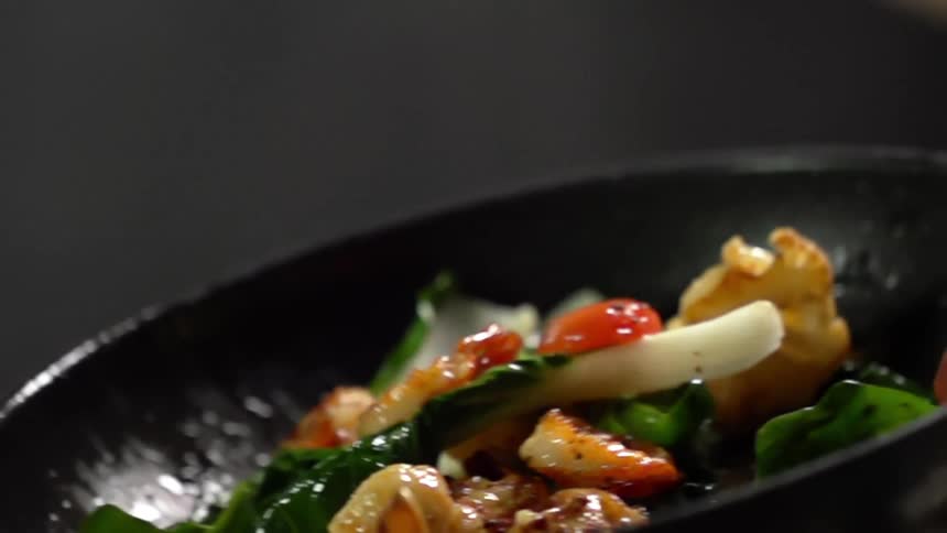 A mix of vegetables and shrimp are tossed in a saute pan