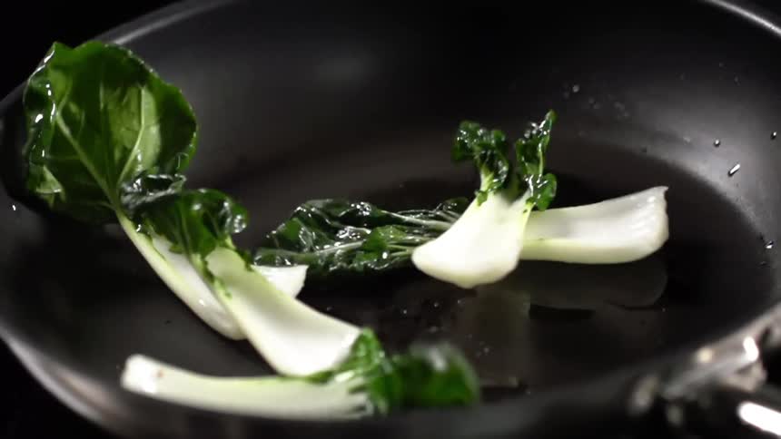 Bok choy is dropped into a pan coated in oil