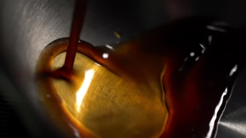 A soy sauce pours into a metal skillet