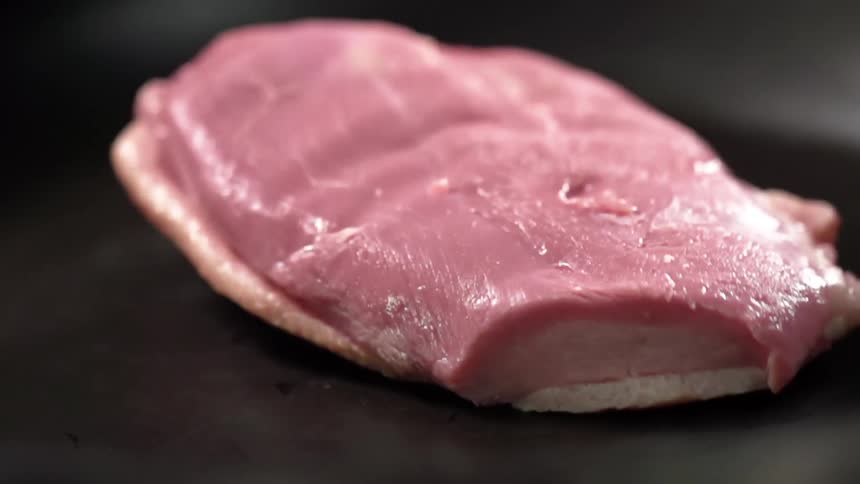 Piece of raw beef falls onto a pan