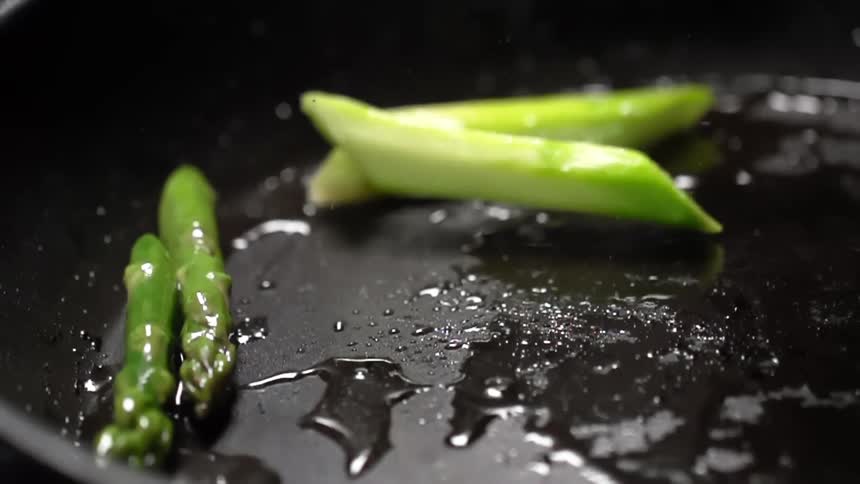 Asparagus frying in a pan with oil