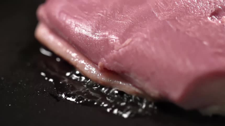 Slice of beef frying over oil on a hot pan