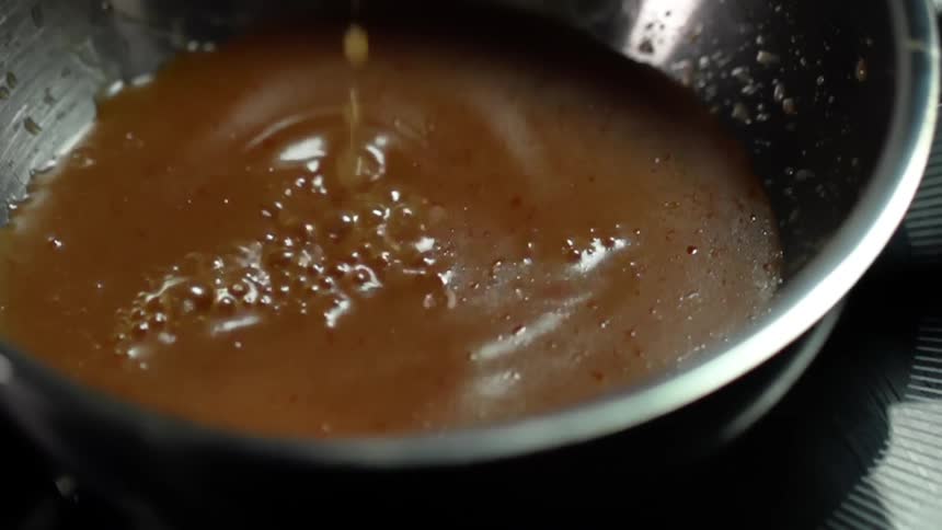Thick brown broth is poured into a saucepan