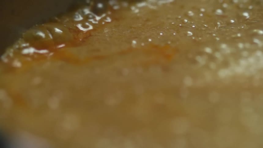 Close up of the surface of a broth boiling inside a pot