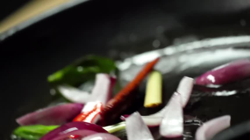 Onions and peppers are shaken and turned in a hot wok