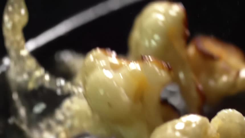 Cauliflower being tossed while frying in an oily skillet