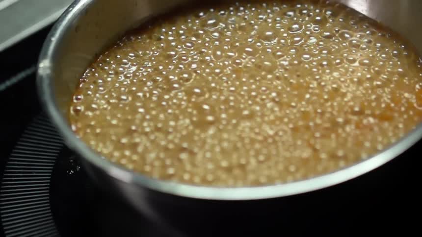 Brown broth in a stainless saucepan boils and bubbles