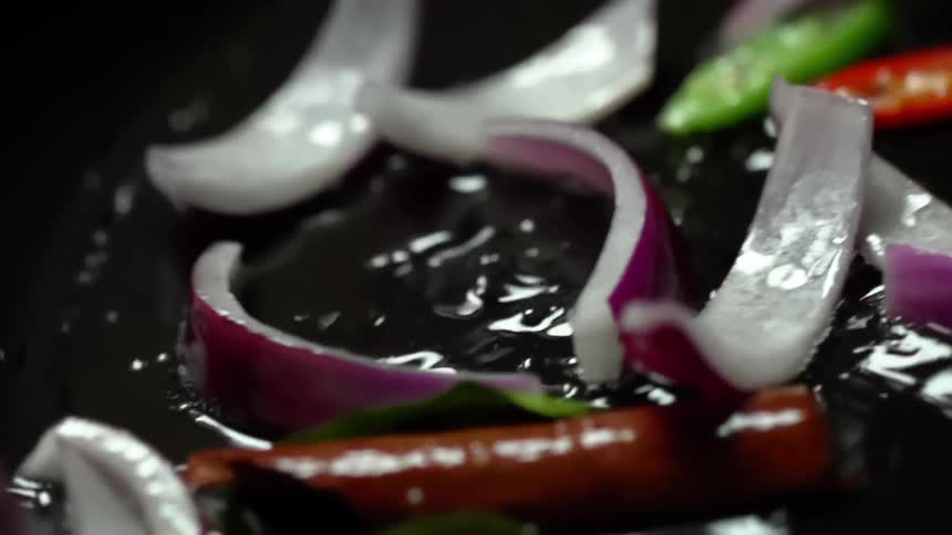 Vegetables turning and tossing in water inside a cast iron pan