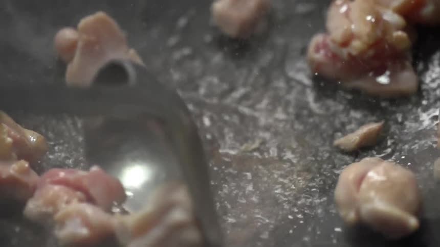 Salmon cubes are being cooked in a black skillet
