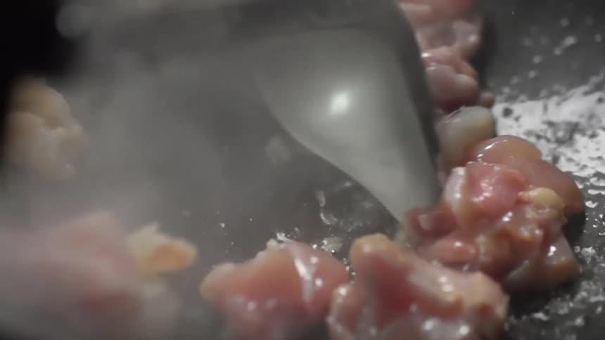 A cook cooks shrimp and fish in a skillet