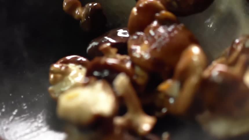Shiitake mushrooms being cooked in a wok with oil