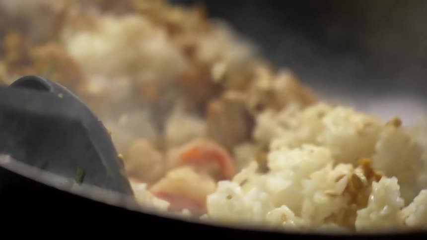 Rice and shrimps tossed while cooking inside a steaming hot wok