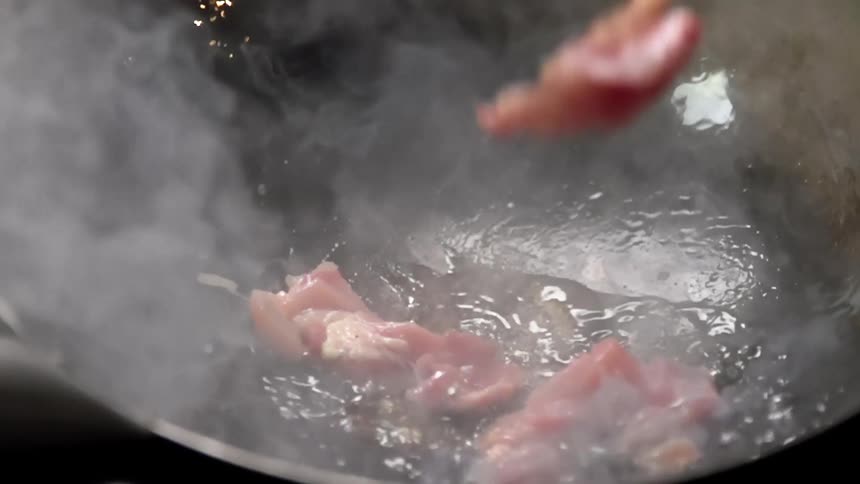 Chopped meat tossed into hot steaming water inside a wok