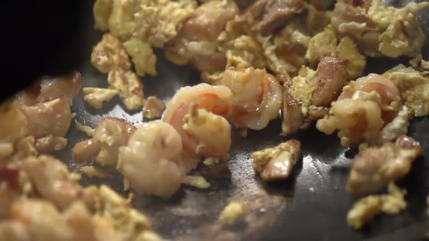 Shrimps and eggs being scrambled in a wok with a spatula