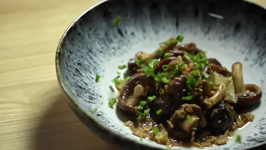 Onions dropping in a bowl with shiitake mushrooms