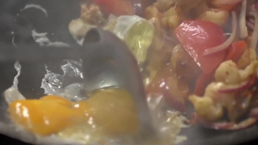 Eggs and vegetables being cooked in a hot steaming pan