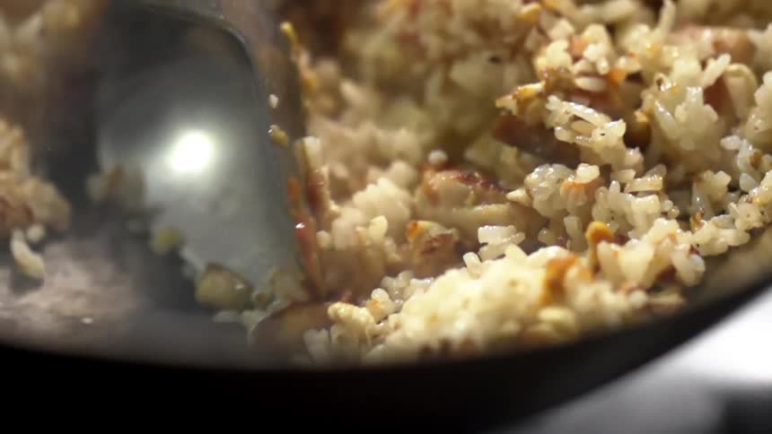 Rice with sea food being tossed while cooking inside a steaming hot wok