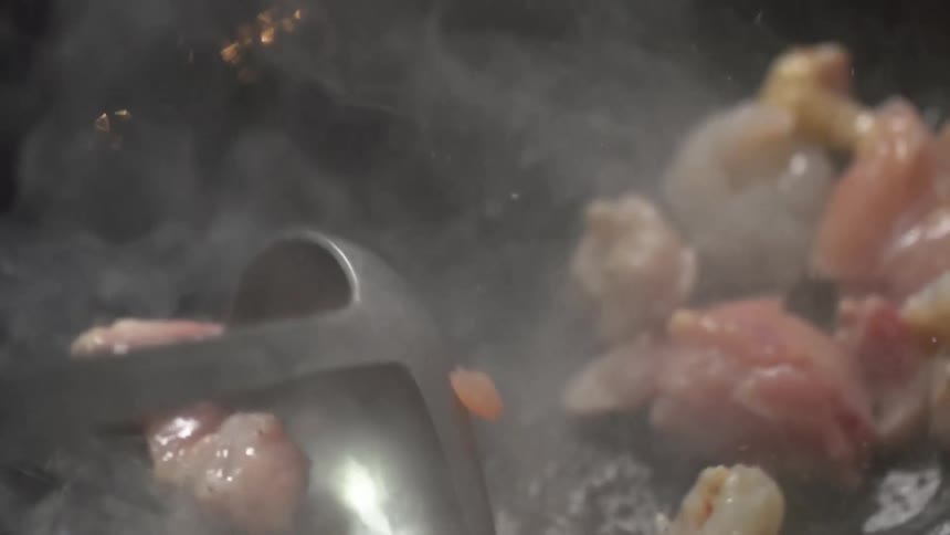 Chicken and shrimps are stirred in a hot wok