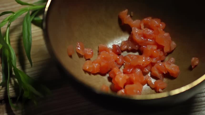 FInely cut salmon being dropped into a bowl