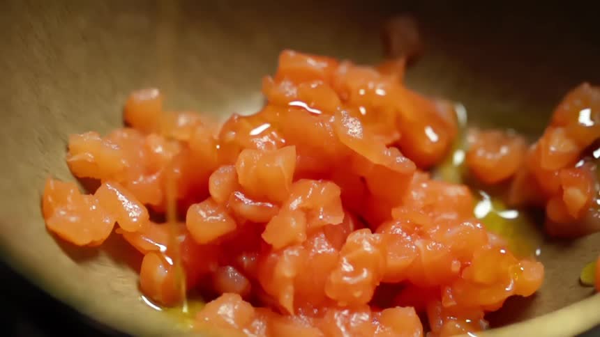 Olive oil is being poured onto thinly cut salmon