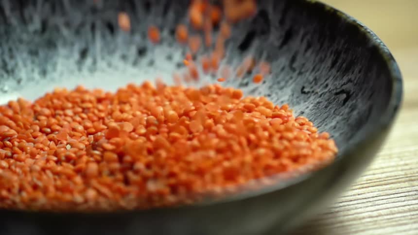 Red lentils fall into a bowl