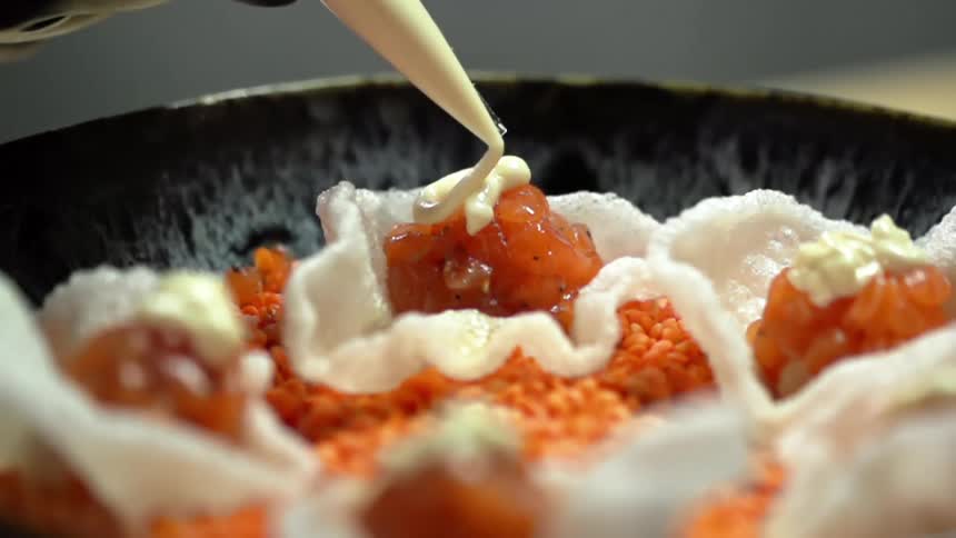 A piping bag is used to top chopped and diced salmon with a creamy sauce
