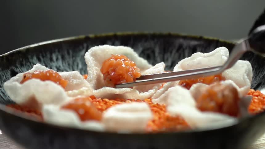 A cook puts cut salmon to a rice chip