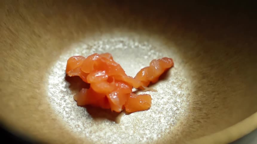 Small diced pieces of salmon are dropped into an empty bowl