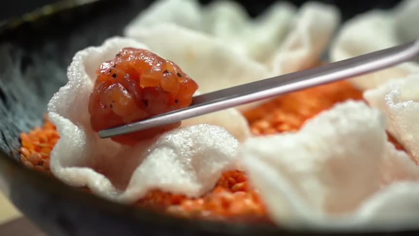 Cut seasoned salmon being placed to a rice chip