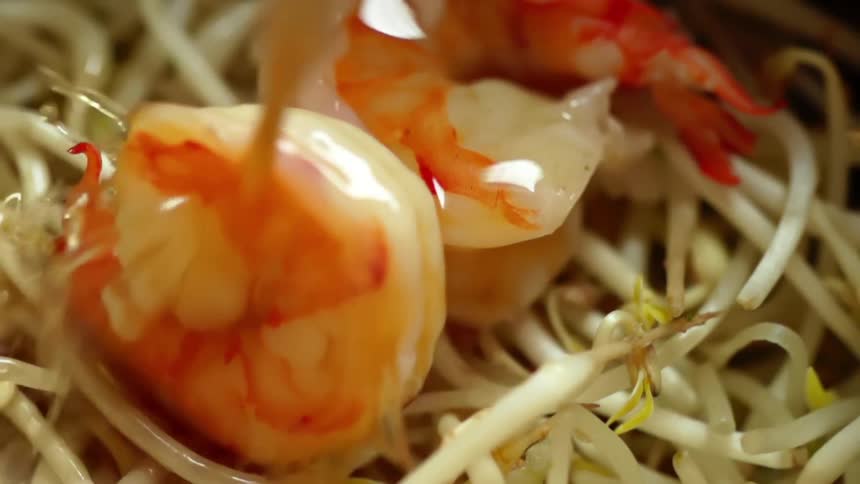 Broth pouring over shrimp laying on bean sprouts
