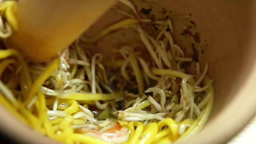 Bean sprouts and shrimps mixed with dark sauce on a bowl