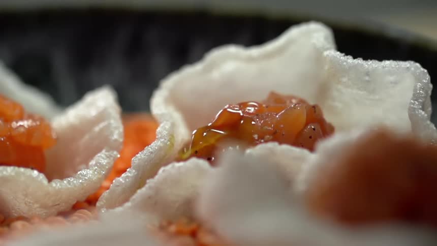 Oil drips down onto diced salmon in a white rice chip