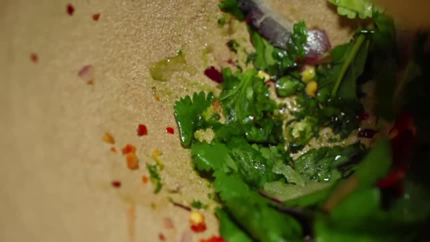 Cilantro and spices being smashed in a mortar with a pestle