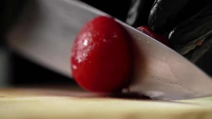 A person cuts a tomato in half