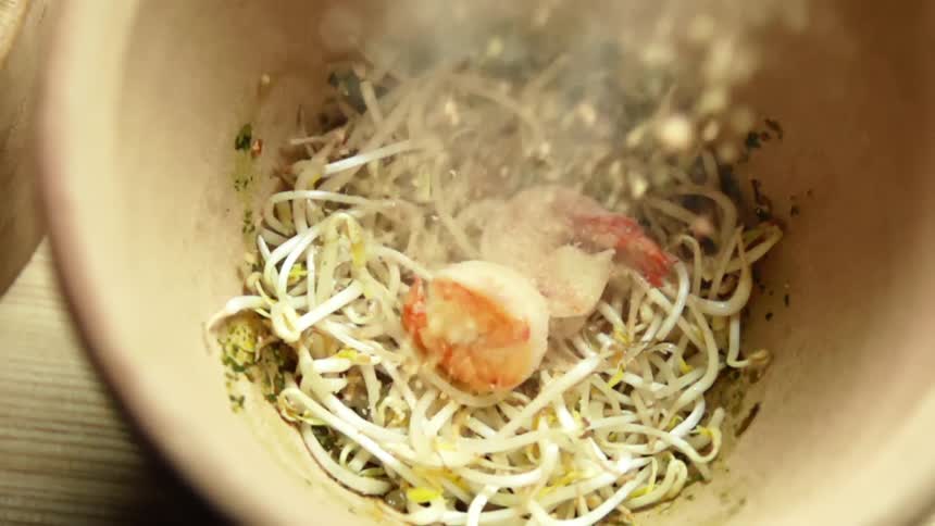 Seasoning is sprinkled onto bean sprouts and shrimps in a bowl