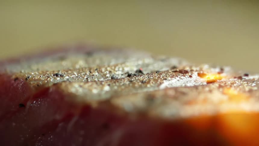 A tuna steak is being grilled over a strong flame