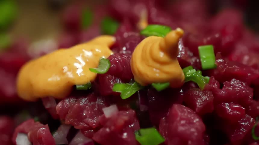 Yellow sauce is being poured onto a tuna tartare