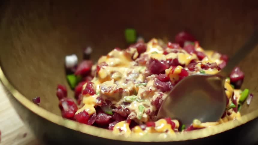 Tuna tartare is being mixed in the bowl with a spoon