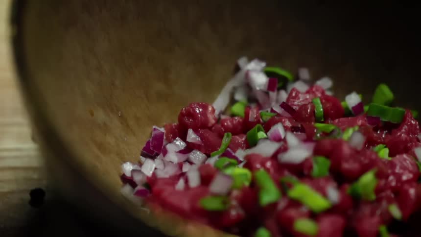 Finely cut onions falling into a bowl with minced tuna